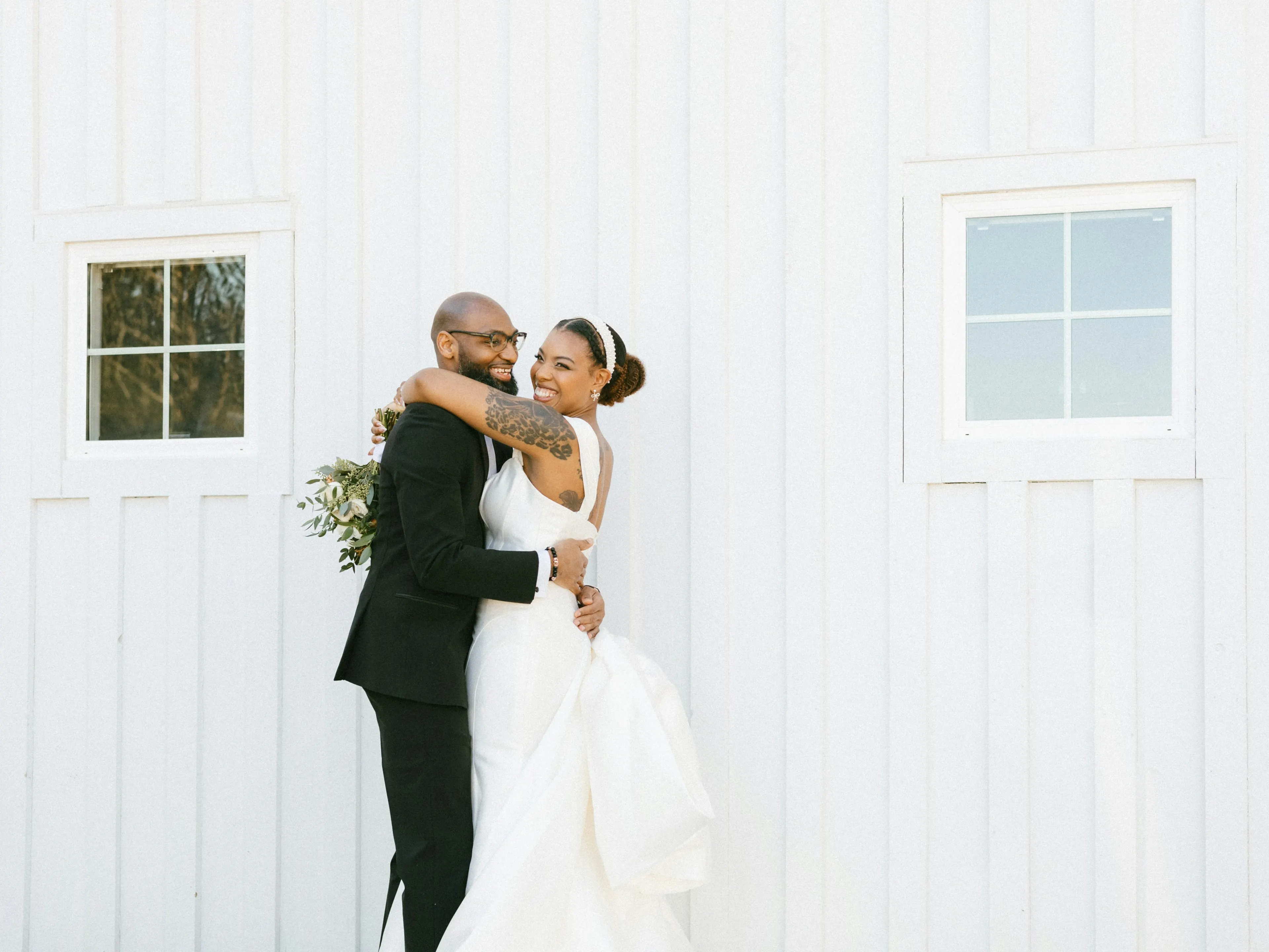 Groom lifting the bride outside a white clapboard house